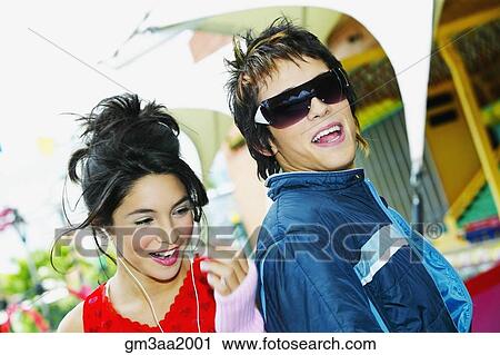Stock Image - Young Hispanic couple smiling at carnival. Fotosearch
