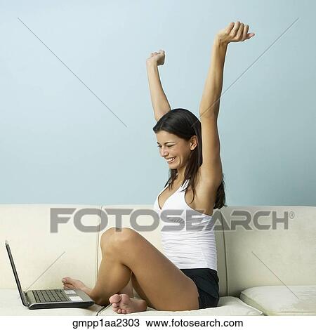 Young Hispanic woman cheering with laptop on sofa View Large Photo Image Stock Image - Young Hispanic woman cheering with laptop on sofa. Fotosearch