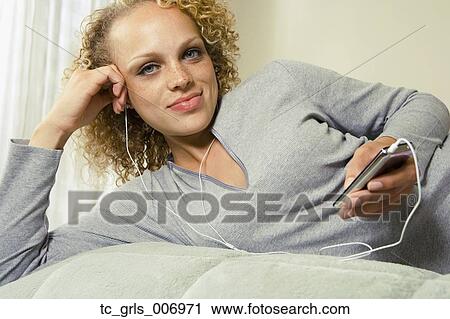Young woman listening to mp3 player in bed View Large Photo Image Stock Image - Young woman listening to mp3 player in bed. Fotosearch
