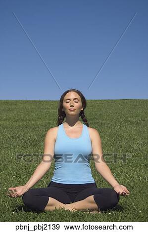 Young woman meditating in field View Large Photo Image Stock Photo - Young woman meditating in field. Fotosearch