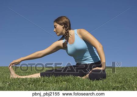 Stock Photography - Young woman stretching in field. Fotosearch