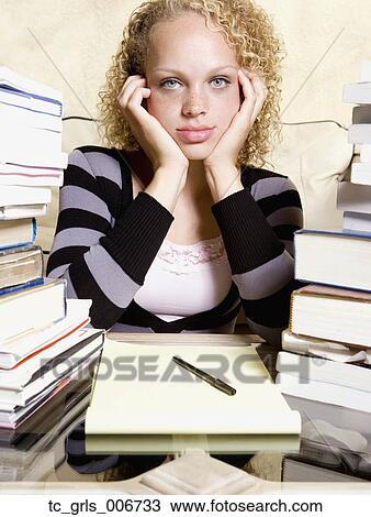 Young woman studying at desk with large stacks of books and notepad View Large Photo Image Stock Image - Young woman studying at desk with large stacks of books and notepad. Fotosearch