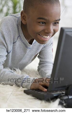 Stock Image - African boy typing on laptop. Fotosearch