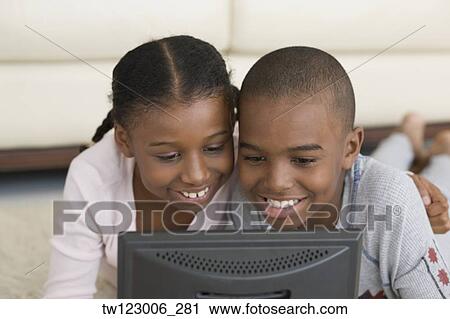 Stock Image - African brother and sister looking at laptop. Fotosearch