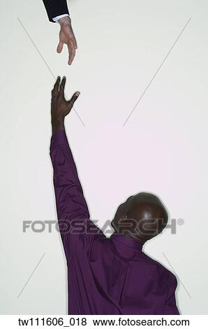 Stock Photo - African businessman reaching up for hand. Fotosearch