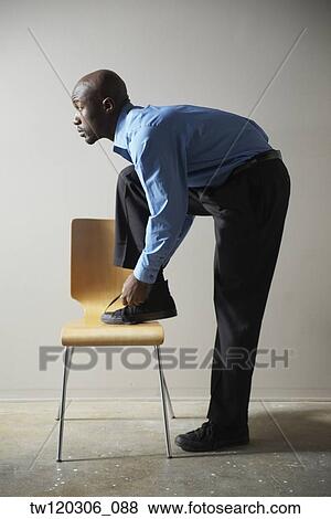 African businessman tying shoe on chair View Large Photo Image Stock Photo - African businessman tying shoe on chair. Fotosearch