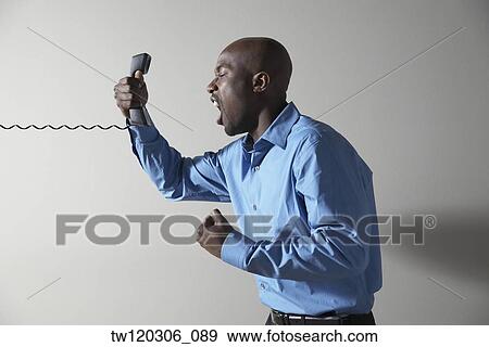 African businessman yelling into telephone View Large Photo Image Stock Photo - African businessman yelling into telephone. Fotosearch