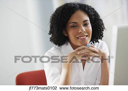 Stock Image - African businesswoman holding pen. Fotosearch