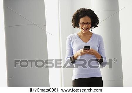 Stock Image - African businesswoman looking at cell phone. Fotosearch