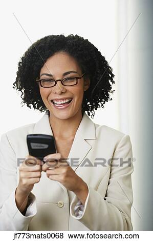 Stock Photo - African businesswoman looking at cell phone. Fotosearch