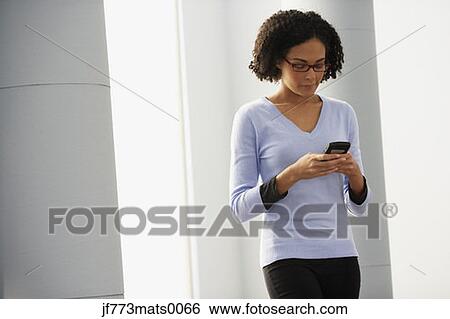 Stock Photograph - African businesswoman looking at cell phone. Fotosearch