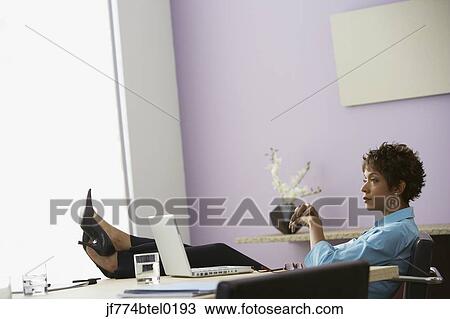 African businesswoman resting feet on desk View Large Photo Image Stock Image - African businesswoman resting feet on desk. Fotosearch