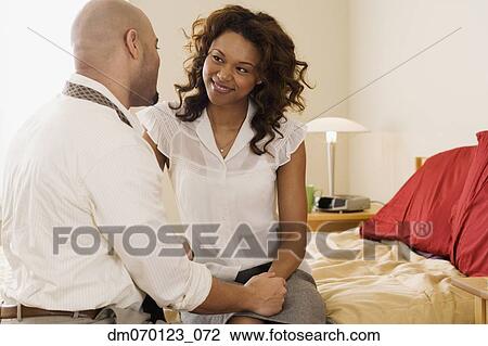 Stock Image - African couple smiling at each other on bed. Fotosearch