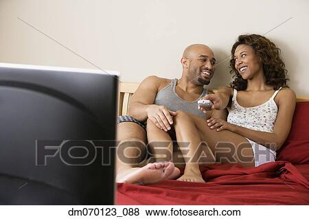 Stock Photo - African couple watching television in bed. Fotosearch