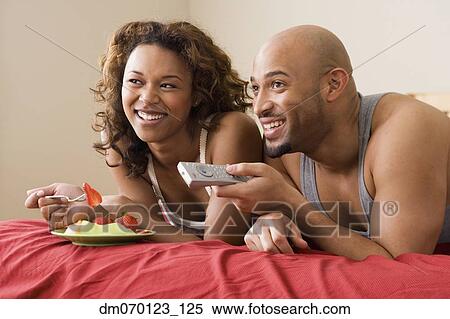 African couple watching television in bed View Large Photo Image Stock Photography - African couple watching television in bed. Fotosearch