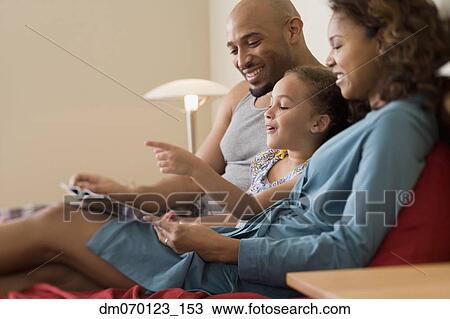 Stock Image - African family reading in bed. Fotosearch