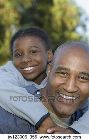 Stock Photograph - African father giving daughter piggyback ride. Fotosearch