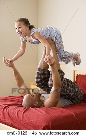 Stock Photography - African girl balancing on father’s feet. Fotosearch