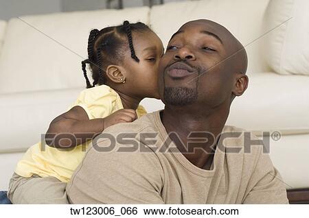 Stock Photograph - African girl kissing father’s cheek. Fotosearch