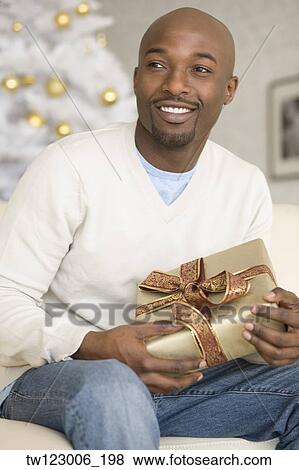 Stock Photo - African man holding Christmas gift. Fotosearch