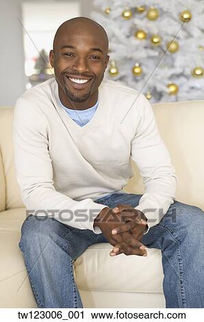 Stock Image - African man sitting on sofa. Fotosearch