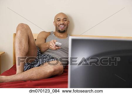 African man watching television in bed View Large Photo Image Picture - African man watching television in bed. Fotosearch