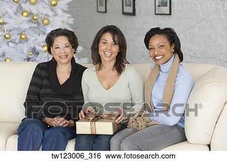 Stock Photograph - African mother and adult daughters with Christmas gift. Fotosearch