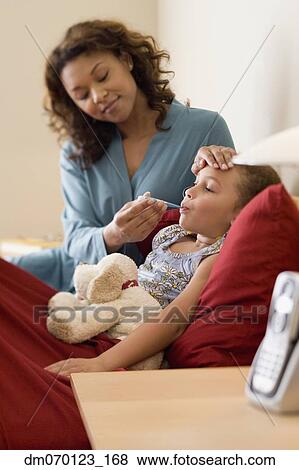 Stock Photo - African mother taking daughter’s temperature. Fotosearch
