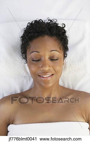 Stock Image - African woman laying on spa table. Fotosearch