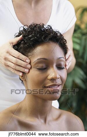 Picture - African woman receiving facial massage. Fotosearch