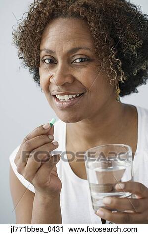 Stock Image - African woman taking pill. Fotosearch