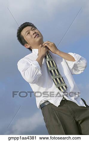 Stock Image - Asian businessman adjusting necktie. Fotosearch