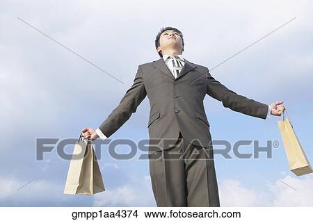Asian businessman holding shopping bags View Large Photo Image Picture - Asian businessman holding shopping bags. Fotosearch