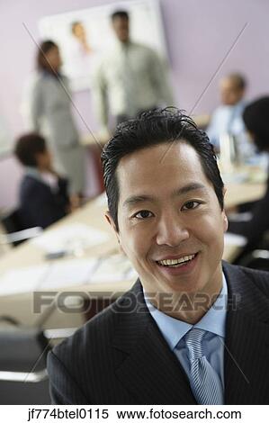 Asian businessman with coworkers in background View Large Photo Image Stock Photography - Asian businessman with coworkers in background. Fotosearch