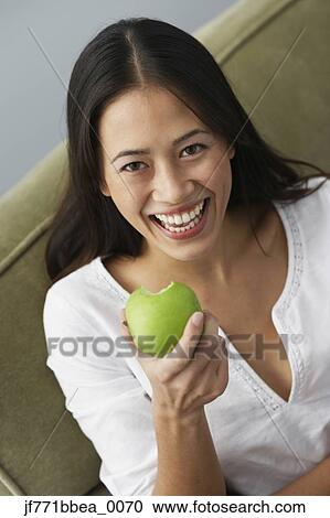 Stock Image - Asian woman eating apple. Fotosearch