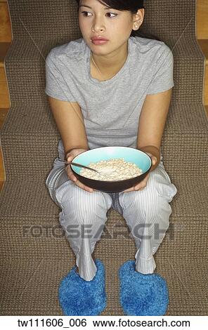 Asian woman eating cereal on stairs View Large Photo Image Stock Photograph - Asian woman eating cereal on stairs. Fotosearch