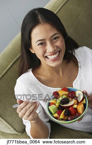Picture - Asian woman eating fruit salad. Fotosearch