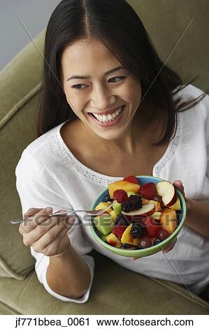 Stock Image - Asian woman eating fruit salad. Fotosearch