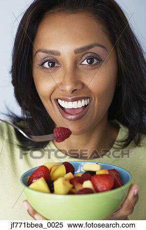 Stock Photography - Asian woman eating fruit salad. Fotosearch