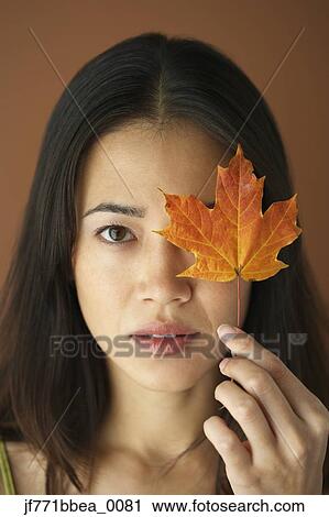 Asian woman holding autumn leaf over eye View Large Photo Image Stock Image - Asian woman holding autumn leaf over eye. Fotosearch