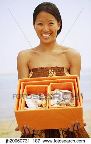 Asian woman holding box of seashells View Large Photo Image Stock Photo - Asian woman holding box of seashells. Fotosearch