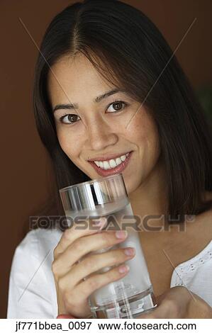 Asian woman holding glass of water View Large Photo Image Stock Photo - Asian woman holding glass of water. Fotosearch