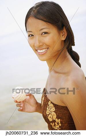 Asian woman holding seashell View Large Photo Image Stock Photograph - Asian woman holding seashell. Fotosearch