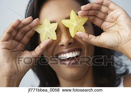 Asian woman holding star fruits over eyes View Large Photo Image Stock Photo - Asian woman holding star fruits over eyes. Fotosearch