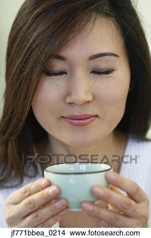 Picture - Asian woman holding tea cup. Fotosearch