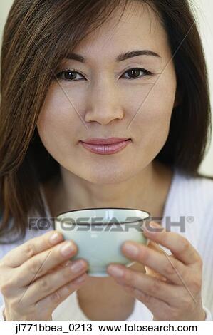 Stock Image - Asian woman holding tea cup. Fotosearch