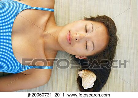 Asian woman laying next to seashell View Large Photo Image Stock Image - Asian woman laying next to seashell. Fotosearch
