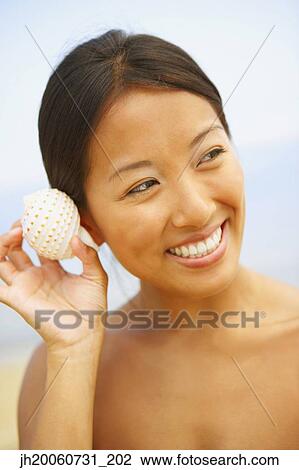 Asian woman listening to seashell View Large Photo Image Stock Image - Asian woman listening to seashell. Fotosearch