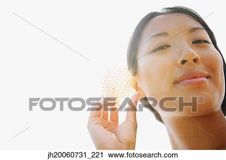 Asian woman listening to seashell View Large Photo Image Stock Image - Asian woman listening to seashell. Fotosearch