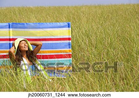 Asian woman sitting in field View Large Photo Image Picture - Asian woman sitting in field. Fotosearch